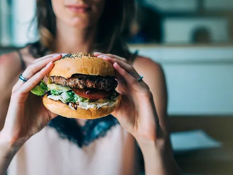 chica borrosa con hamburguesa en manos